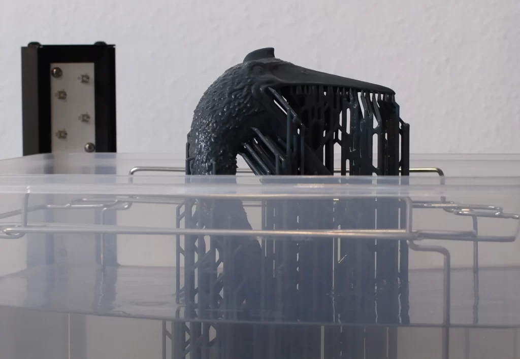 Bild vom Abwaschen des überschüssigen Harzes vom fertig gedruckten Objekt mit dem Elegoo Jupiter SE 3D-Drucker.